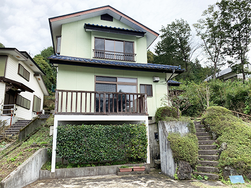 傾斜地にライトグリーンの外壁